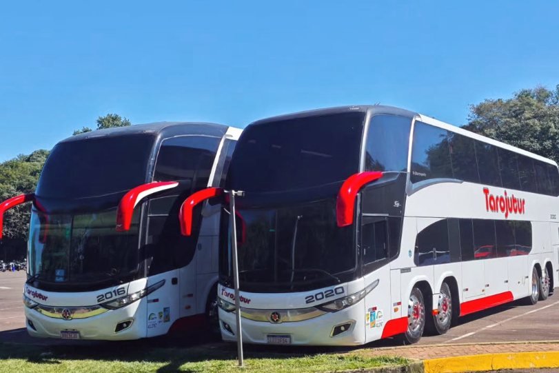 Dois ônibus rodoviários da Tarojutur estacionados lado a lado sob céu azul, um deles de dois andares